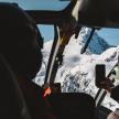 a group of people sitting in a helicopter looking at a mountain