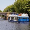 a blue and white boat on a river near a bridge