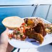 a person holding a plate of food on a boat