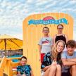 a group of children posing in front of a surfboard