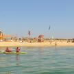 two people in a kayak in the water near a beach