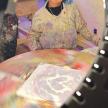a woman standing next to a table with a painting