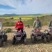 a group of four men standing on four wheelers