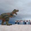 a group of people standing next to a dinosaur statue