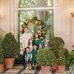 a man and his family standing in front of a christmas tree