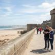 a man and a woman standing on a wall next to a beach