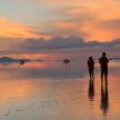 a couple standing on the beach watching the sunset