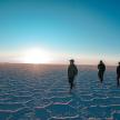 three men walking in the desert with the sun in the background