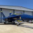 a blue fighter jet parked in front of a hangar
