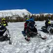 tři lidé jedoucí na sněžných motorkách ve sněhu