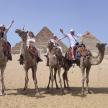 a group of people riding on camels in front of pyramids