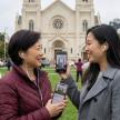 two women holding up their cell phones in front of a church