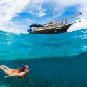 a woman swimming in the ocean next to a boat