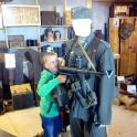 a young boy holding a gun next to a mannequin