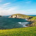 a view of the ocean with a green field and cliffs
