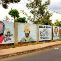 a row of posters on a wall next to a street
