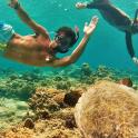 two people swimming in the ocean near a reef