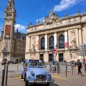 an old car parked in front of a building with a clock tower