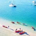 a group of people on a beach with boats in the water