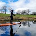 a man standing on an orange paddle board in the water