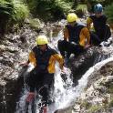 three people in helmets sitting on a waterfall