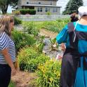 a woman standing next to a mannequin in a garden