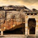 a stone building next to a large rock wall