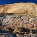 a large mountain with rocks and plants on it