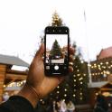 a person holding up a cell phone in front of a christmas tree