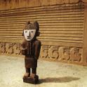 a wooden statue of a person in front of a wall