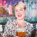 a woman sitting at a table with a glass of beer
