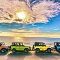 a group of four jeeps parked on the beach