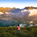 a woman standing on top of a hill overlooking a valley