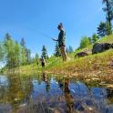 a man is standing next to a pond fishing