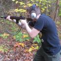 a man in headphones holding a gun in the woods