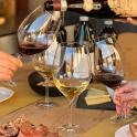 due persone versano il vino nei bicchieri da vino su un tavolo