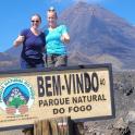 two people standing on top of a sign in front of a mountain