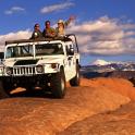 Tres personas sentadas en la parte superior de un jeep en una montaña