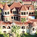 an aerial view of a large house with palm trees