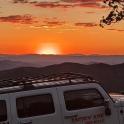 a white truck parked on top of a mountain at sunset