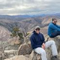 two men sitting on top of a mountain