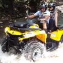 two people riding on a four wheeler through a river