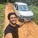 a man giving a thumbs up on a dirt road with a van
