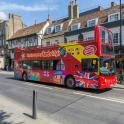 a red double decker bus driving down a street