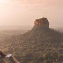 a woman sitting on the edge of a mountain
