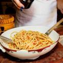 a person is preparing pasta in a bowl with tongs