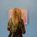 a woman with long curly hair standing in front of a painting