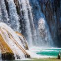a person standing in the water in front of a waterfall