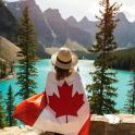 a woman holding a canadian flag looking at a lake