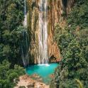 a waterfall in the middle of a forest with a pool of water